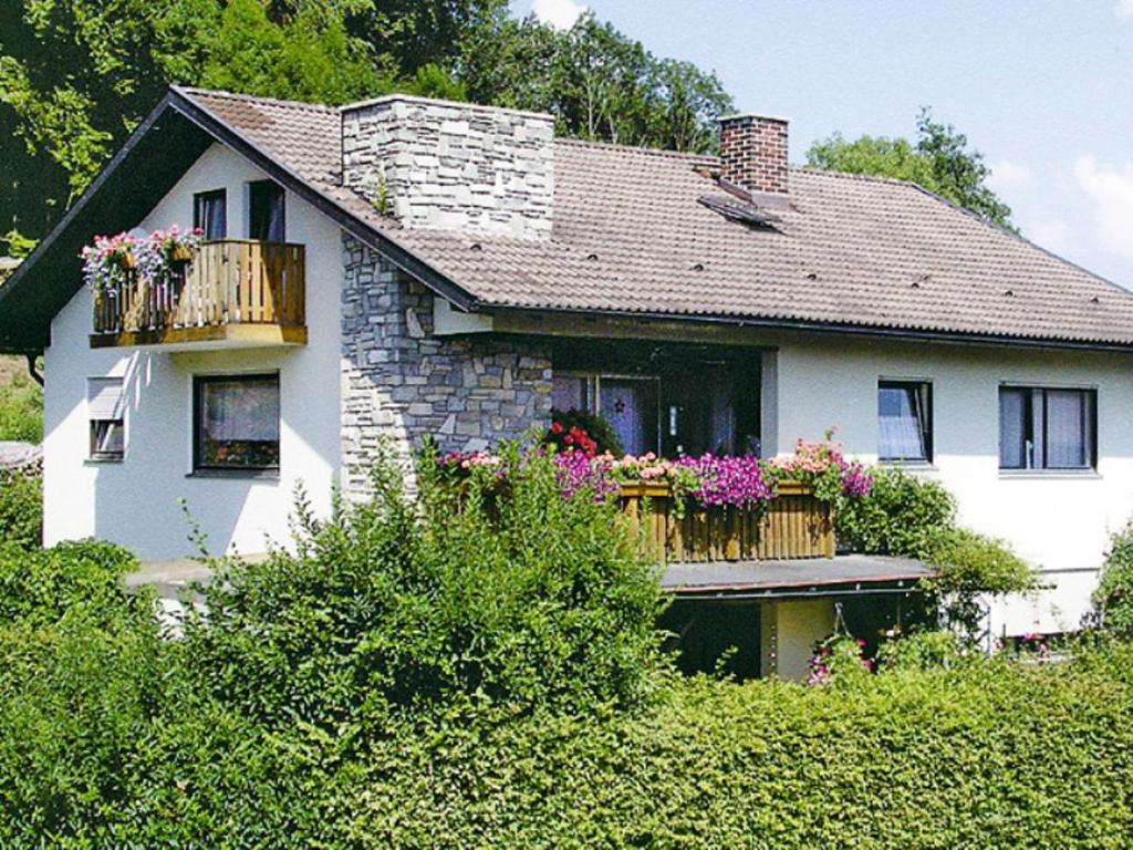 ein weißes Haus mit Blumenkästen auf dem Balkon in der Unterkunft Ferienwohnung Spitzer in Waging am See