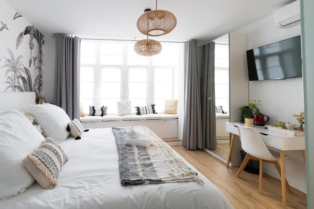 a bedroom with a white bed with a desk and a window at Bilbao Art Lodge Staynnapartments in Bilbao