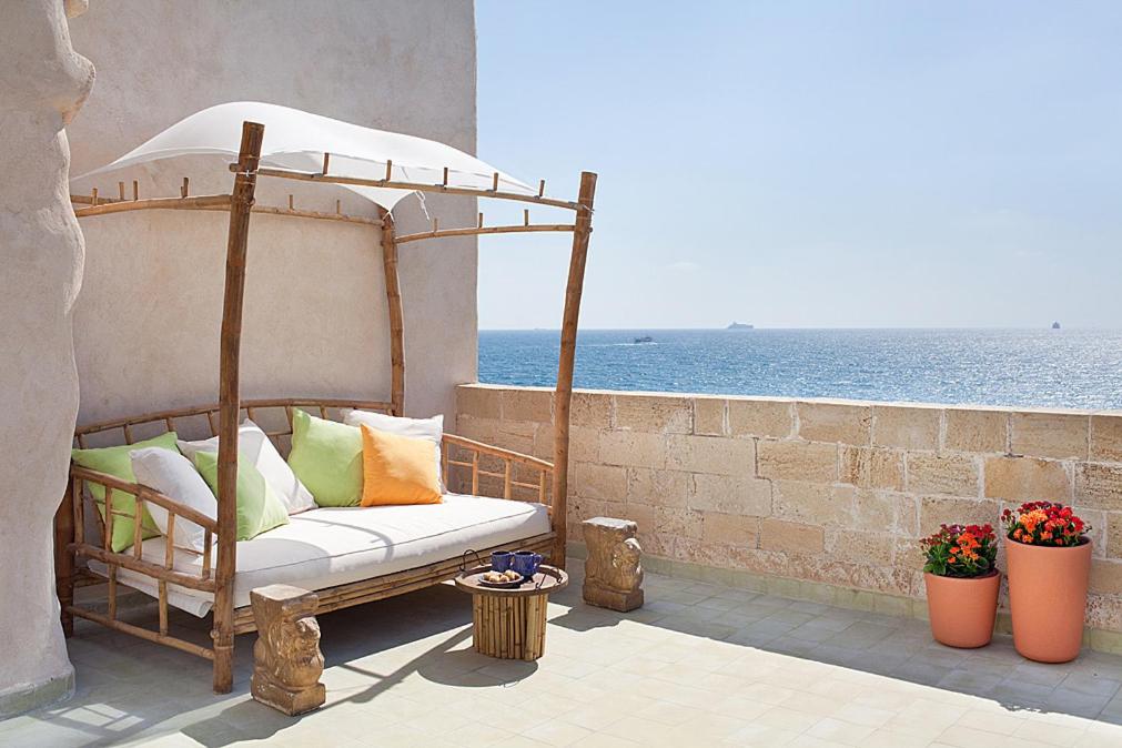 a couch sitting on a patio next to the ocean at Four Hearts - Acre's Sea Side Suite in Acre