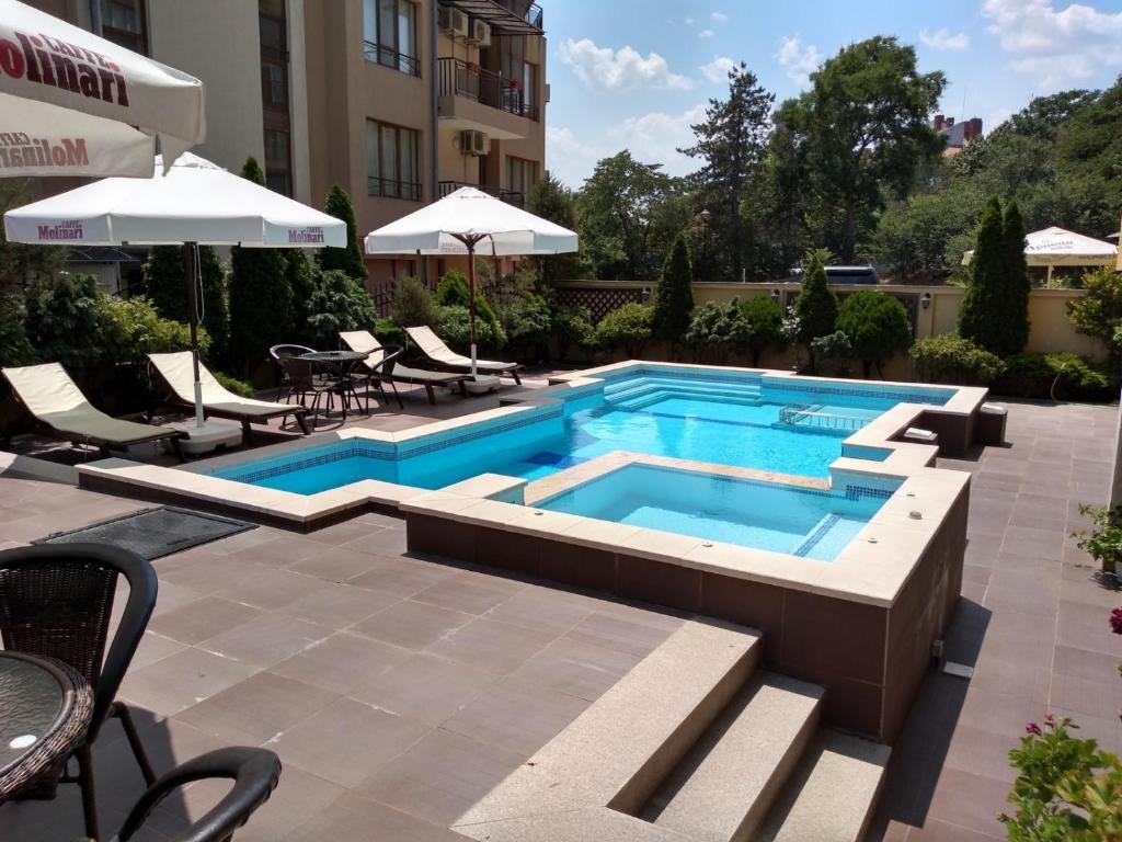 a swimming pool with chairs and an umbrella at Villa Valeev in Sozopol