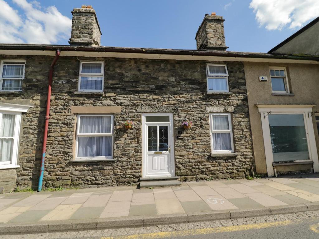 an old stone house with a white door and windows at Arosfa in Bala