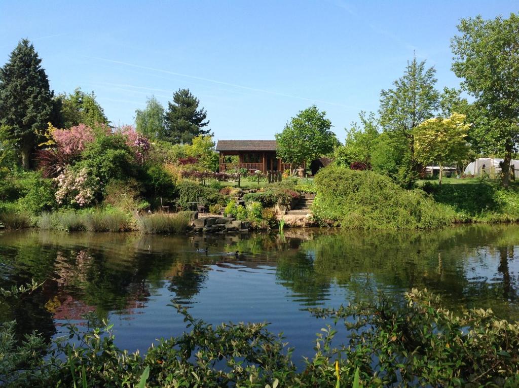 a view of a lake with a house in the background at Lakeside Town Farm in Kingston Blount