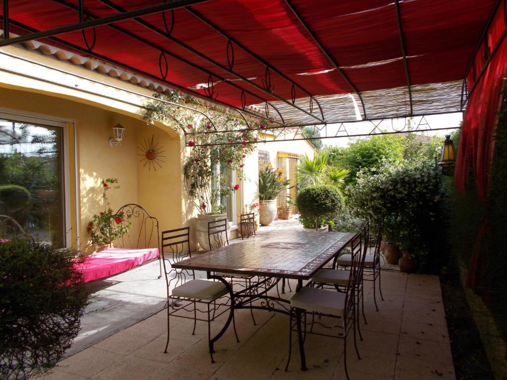 patio ze stołem i krzesłami pod czerwonym sufitem w obiekcie Gîte Aux Amandiers w Fréjus