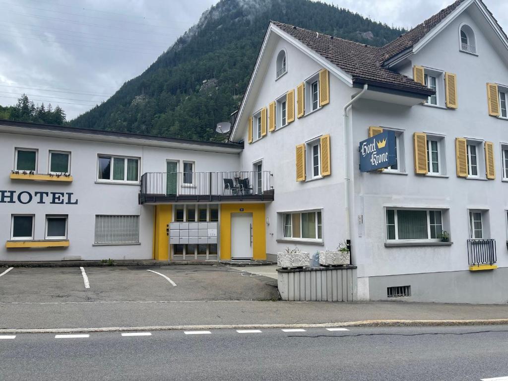 a white hotel with yellow windows and a street at Hotel Krone in Wassen