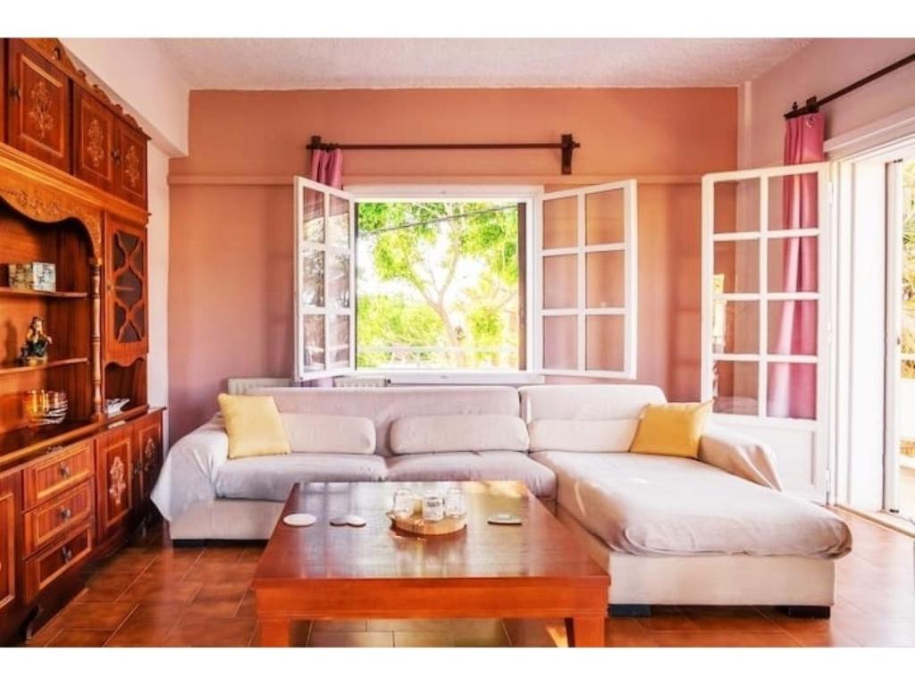 a living room with a white couch and a window at Rena's Hospitality walk to the beach,10min to Chania! in Kato Daratso
