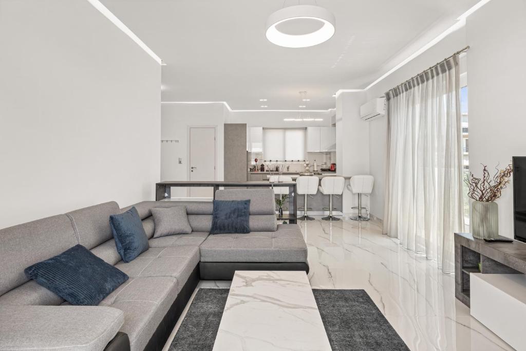 BillyMare central Glyfada apartment في أثينا: غرفة معيشة مع أريكة رمادية ومطبخ