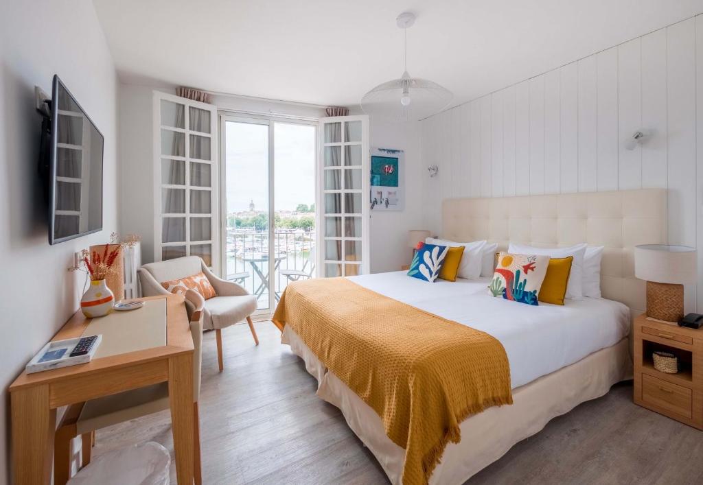 a bedroom with a bed and a table and a chair at Hôtel La Tour de Nesle La Rochelle Vieux Port in La Rochelle
