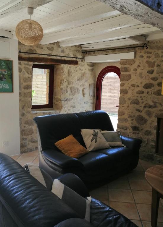 a leather couch in a living room with a stone wall at Le cottage de l&#39;étang in Le Tablier