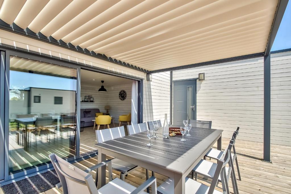 a dining room with a table and chairs on a deck at Chalet pour 8 dans résidence avec piscine chauffée in Brétignolles-sur-Mer