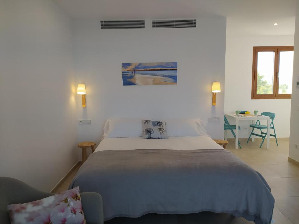 a bedroom with a large bed and a table at Apartamentos Villa Primera in Cala Figuera