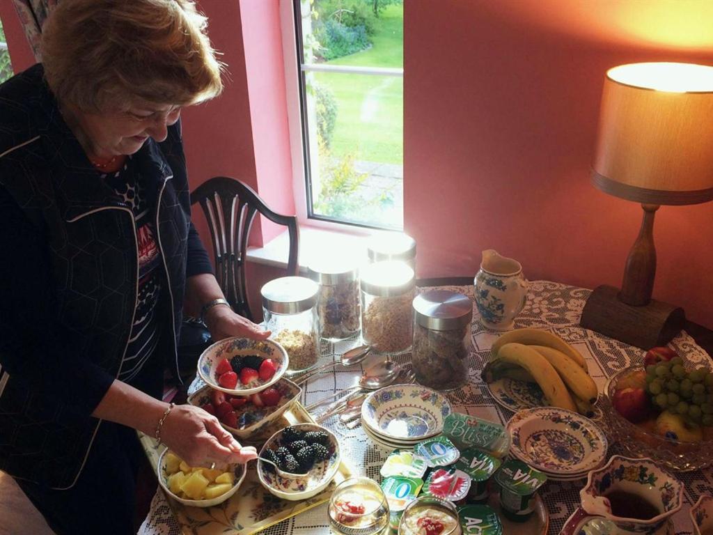 a woman standing at a table with bowls of food at Old Drynie House, in Inverness