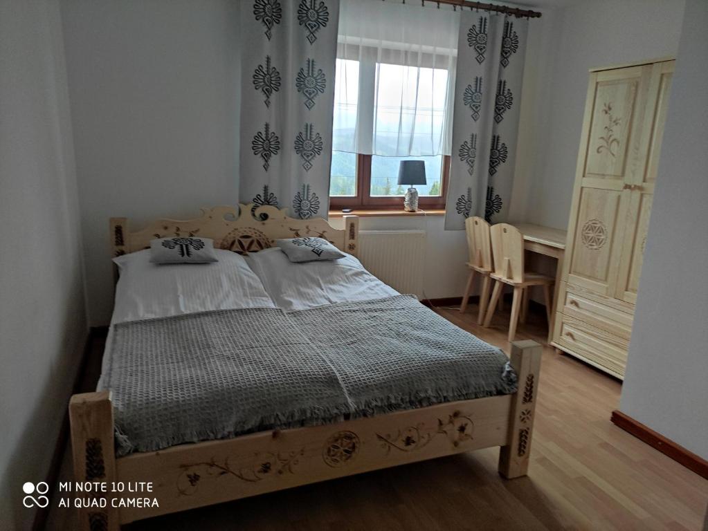 a bedroom with a bed and a desk and a window at Pokoje u Matusa in Gliczarów