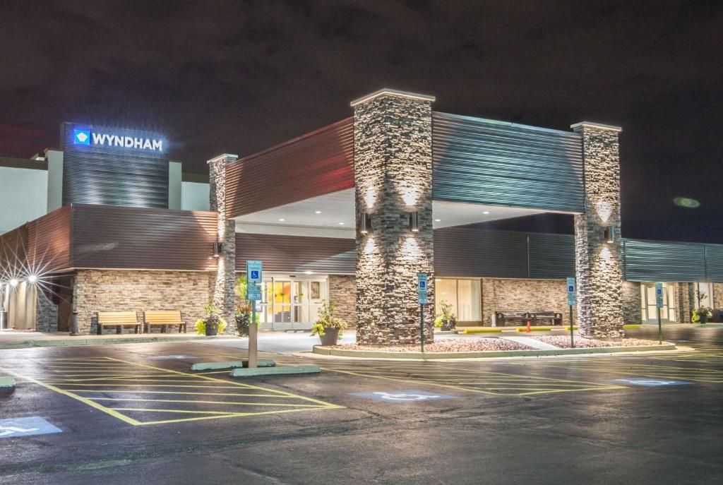 un edificio con un estacionamiento delante de él por la noche en Wyndham Chicago O'Hare en Rosemont