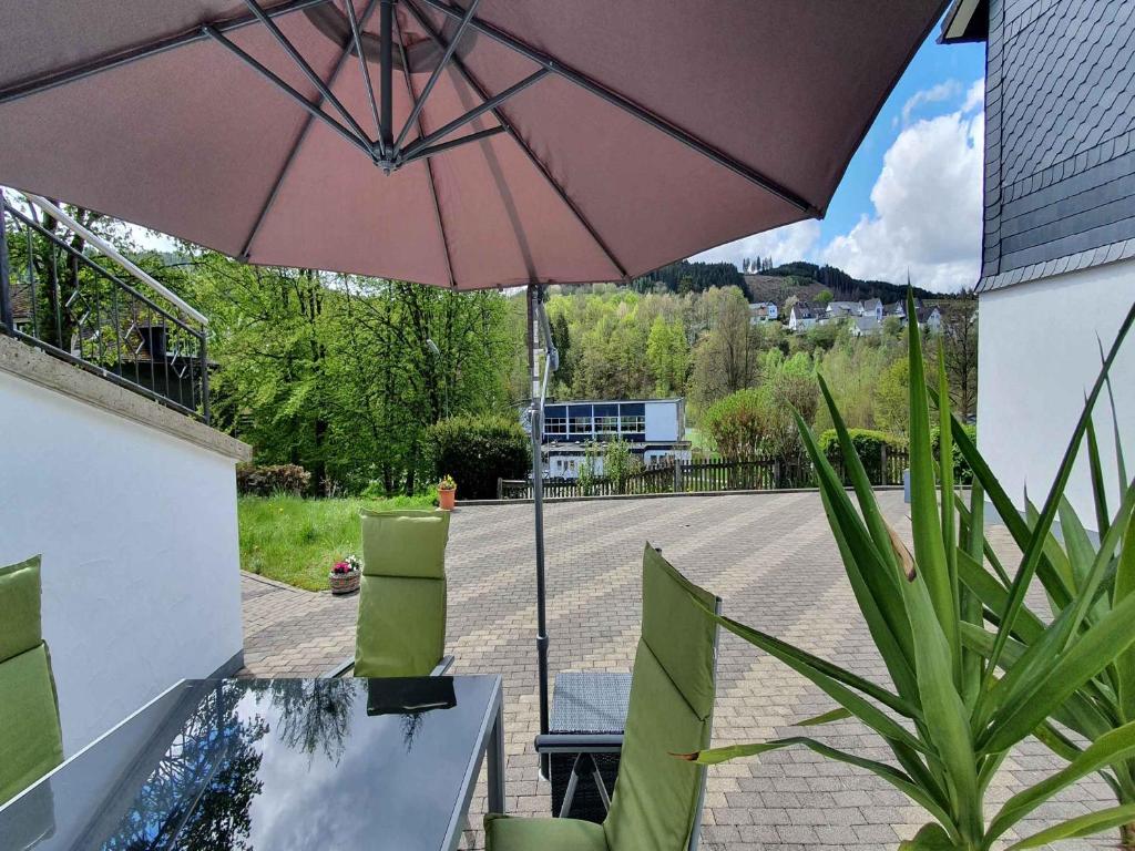 a patio with a table and an umbrella at Ferienwohnung sauerland-ruhe in Schmallenberg