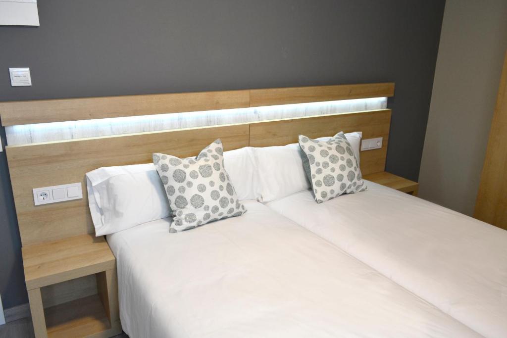 a bed with two pillows on top of it at Alda Catedral in Santiago de Compostela
