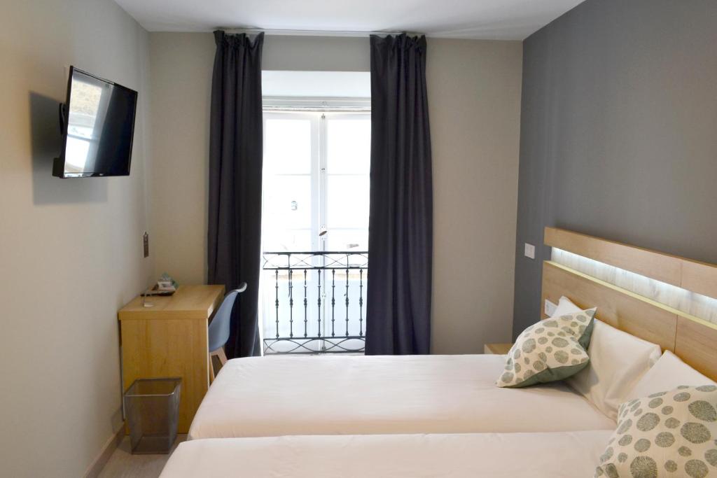 um quarto de hotel com uma cama e uma janela em Alda Catedral em Santiago de Compostela