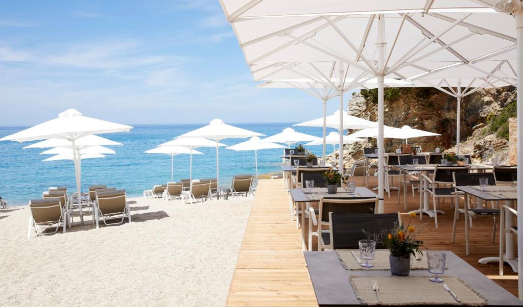 a beach with tables and chairs and umbrellas at Elix, Mar-Bella Collection in Perdika