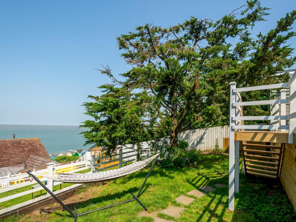 a hammock on the side of a fence with the ocean at Pass the Keys The Beach Treehouse A Splendid Tranquil Retreat in Herne Bay