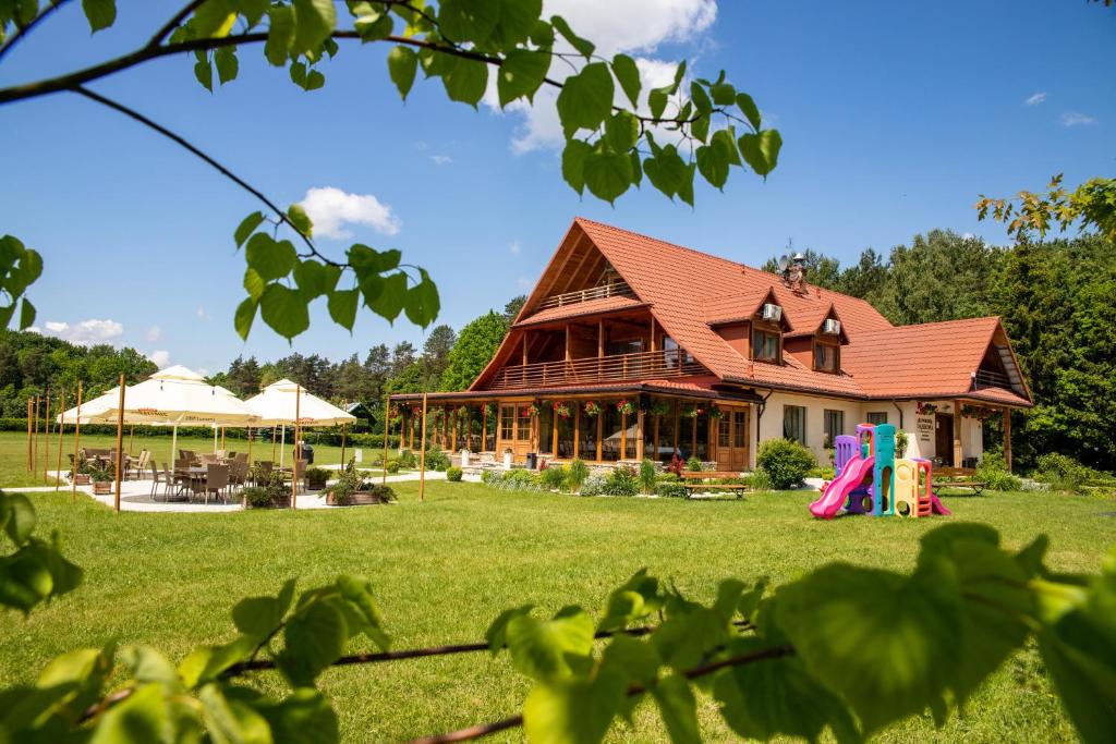 una casa grande con un patio con parque infantil en Dworek Dąbrowa, en Tomaszów Lubelski