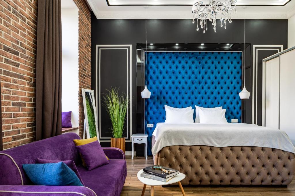 een slaapkamer met een bed en een paarse bank bij Theatre Boutique Apart-Hotel in Kiev