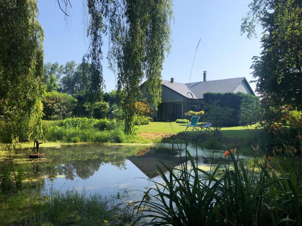 a view of a pond in front of a house at Jardin des Pérelles in Varengeville-sur-Mer