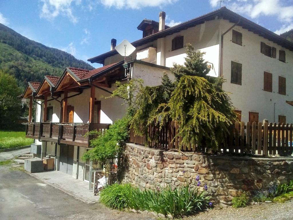 a large white house with a stone wall at casa vacanze in Cogolo