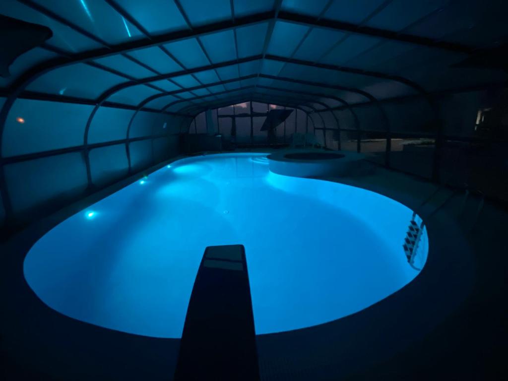 uma piscina com iluminação azul num quarto escuro em Buarcos Luxury Guest house em Figueira da Foz