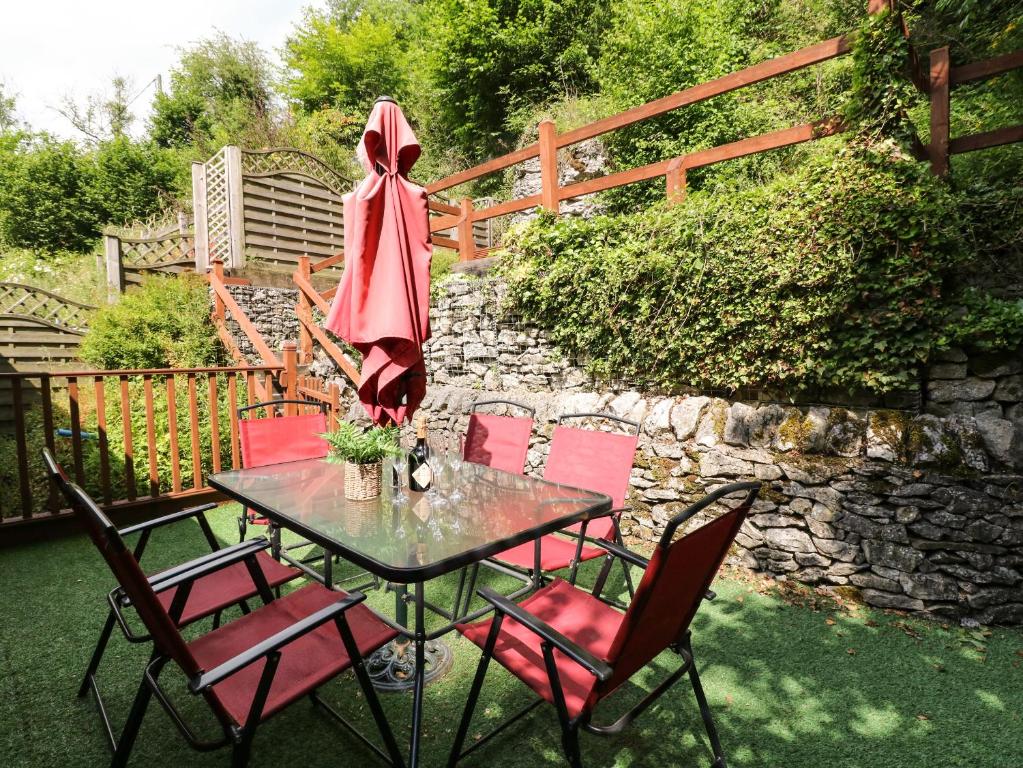 a table with red chairs and a stone wall at The Barn in Buxton