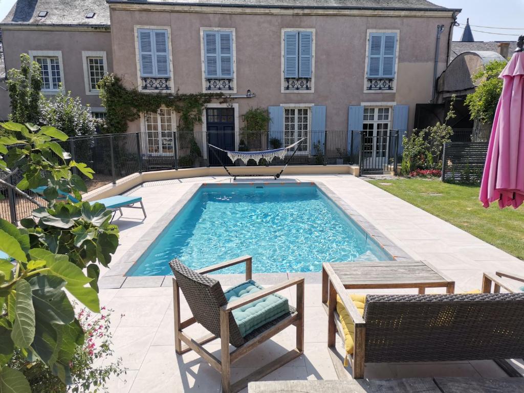 a swimming pool with chairs and a hammock and a house at 5 Grande Rue in Le Lude