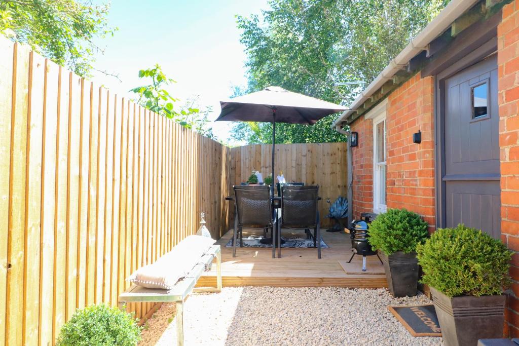 a patio with an umbrella next to a fence at Raffinbow Retreat in Mickleton