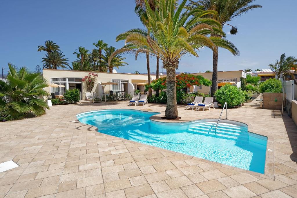 une piscine avec des palmiers et une maison dans l'établissement Bungalows Granada Beach, à Playa del Ingles