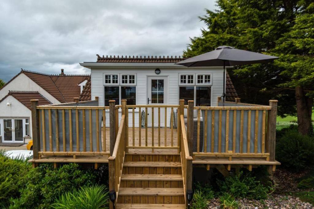 a wooden deck with an umbrella in front of a house at Adorable First Floor 1-bedroom Loft with decking in Omagh
