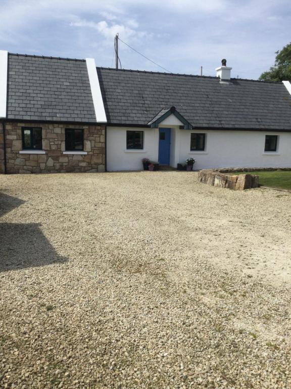 a house with a gravel driveway in front of it at Tullybeggs B&B in Clifden