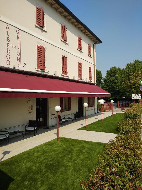budynek z czerwoną markizą obok trawnika w obiekcie Albergo Grifone 1891 w mieście Peschiera del Garda
