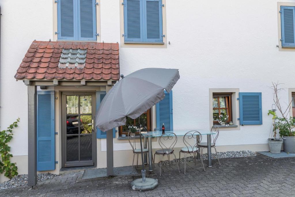 a table with chairs and an umbrella in front of a building at Ferienwohnung Holl-Horn in Gaienhofen