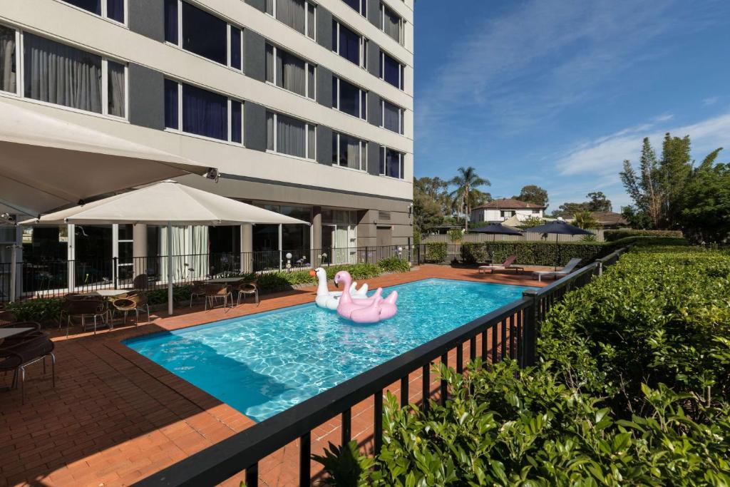 a swimming pool with two pink flamingos in a hotel at Rydges Bankstown in Bankstown
