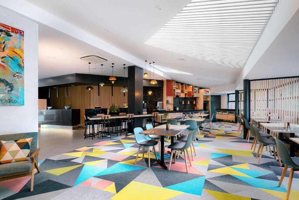 a restaurant with tables and chairs on a colorful floor at Atura Wellington in Wellington