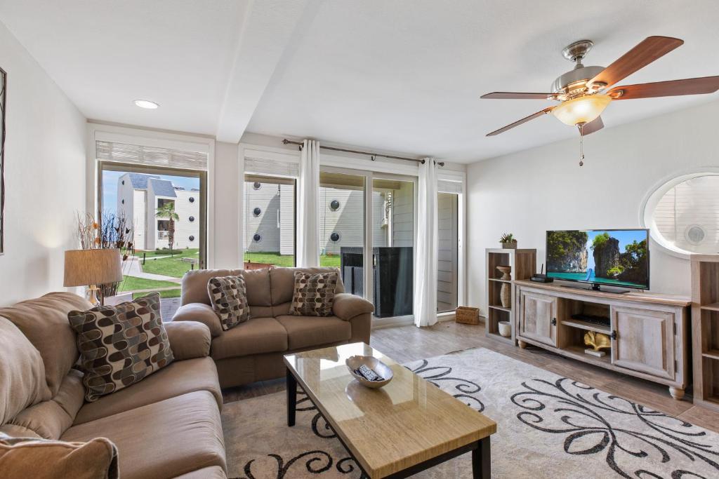 a living room with a couch and a tv at Ground floor, spacious patio and only steps away from beach and pool! in South Padre Island