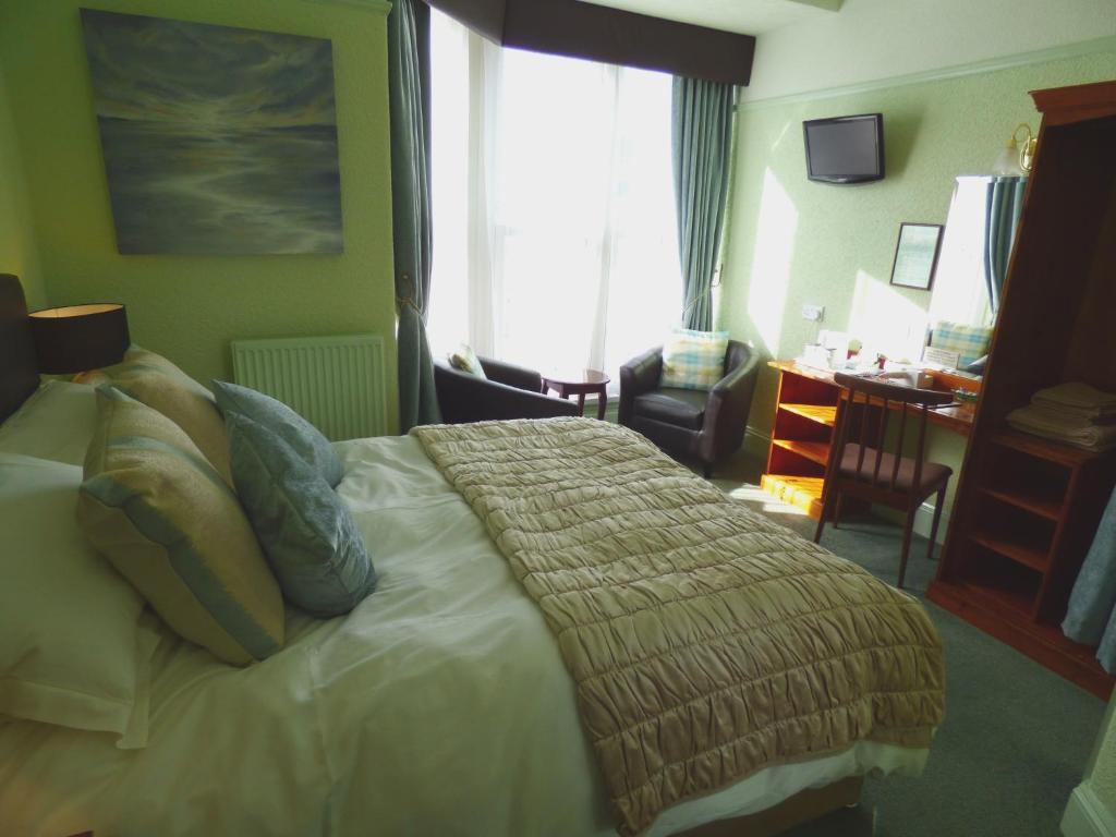 a bedroom with a bed and a desk and a window at Southcliff Guest House in Tenby