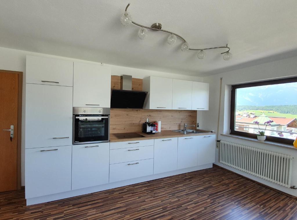 une cuisine avec des placards blancs et une grande fenêtre dans l'établissement Ferienwohnung Sophia, à Innsbruck
