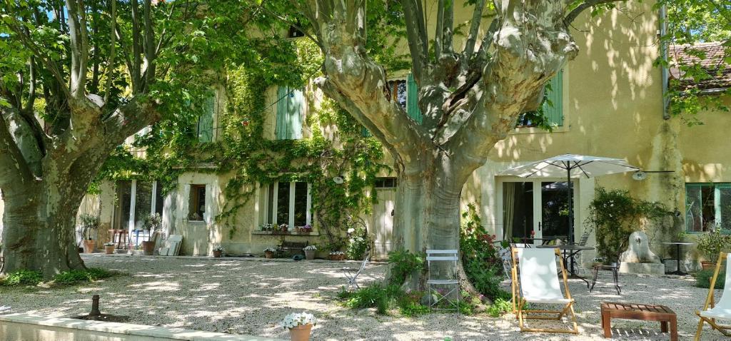 un bâtiment avec des arbres et un parasol devant lui dans l'établissement mas de karlotte, à Pernes-les-Fontaines