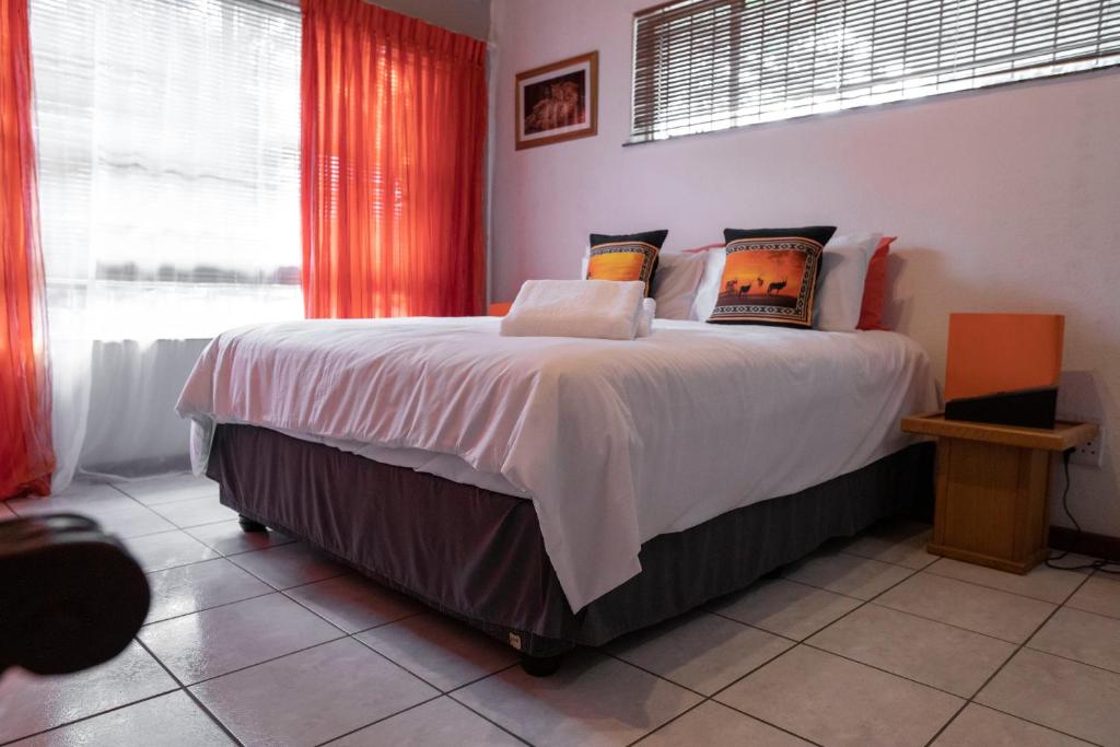 a bedroom with a large bed with red curtains at Lyronne Guest house, Shuttle and Tours in Cape Town