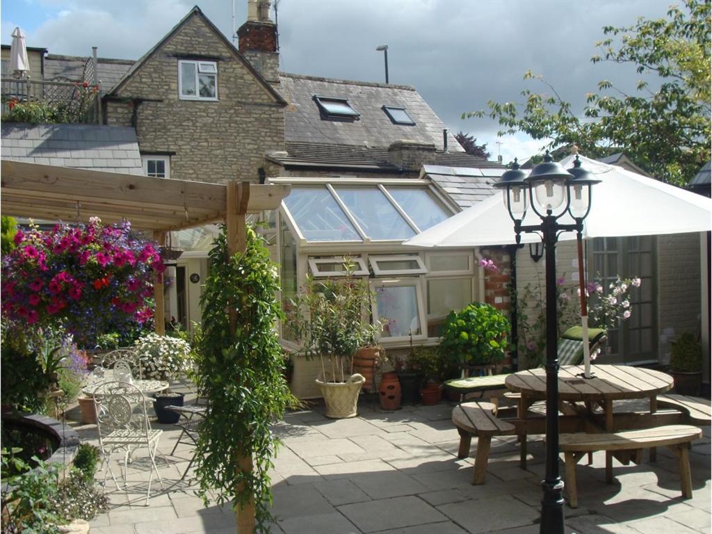 un patio con una mesa y una sombrilla y una casa en The Old Brewhouse, en Cirencester