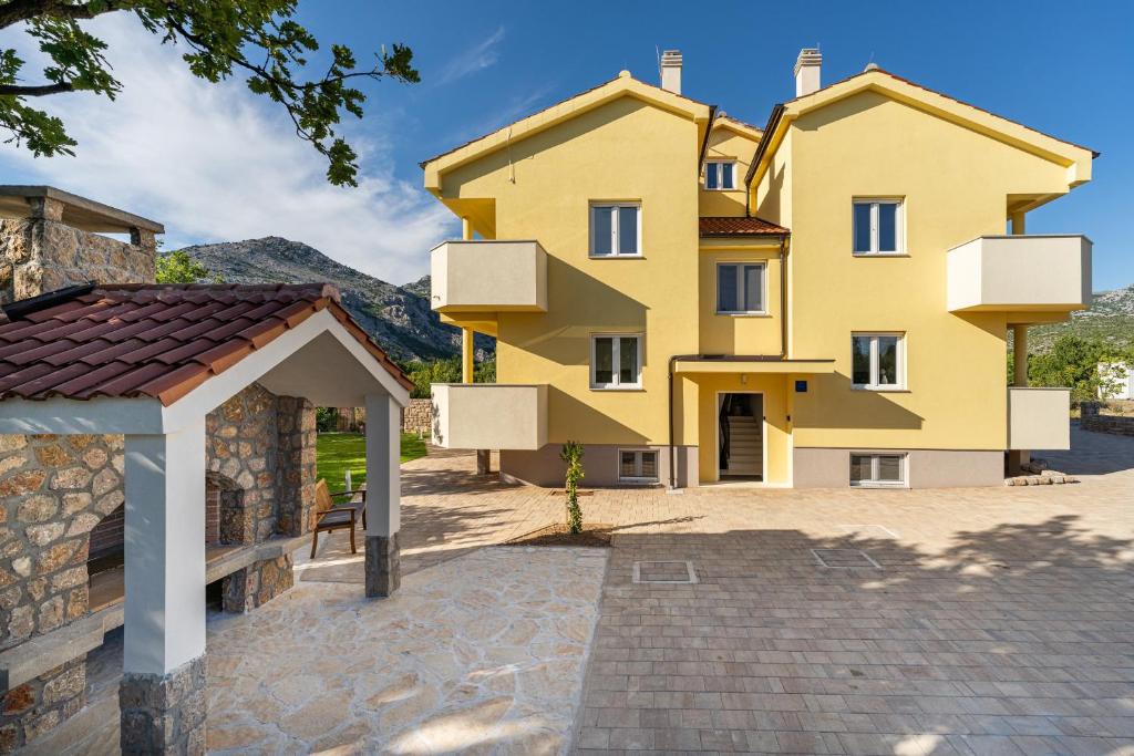 ein gelbes Gebäude mit einem Pavillon davor in der Unterkunft Green Point Paklenica in Starigrad-Paklenica