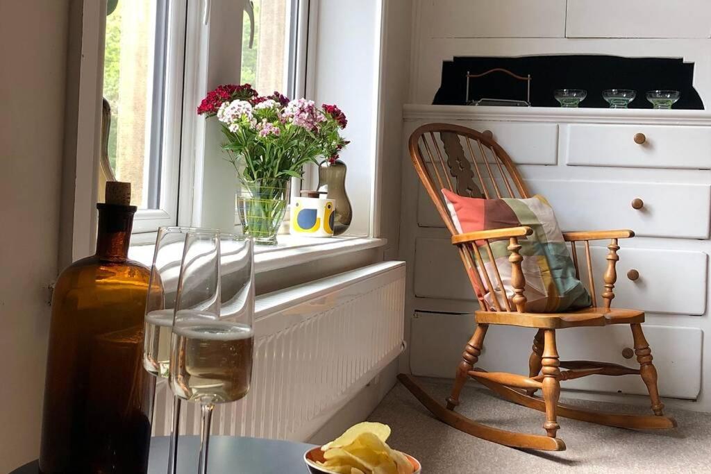 eine Flasche Wein und ein Stuhl im Fenster in der Unterkunft Stylish studio gem in the heart of Hebden in Hebden Bridge