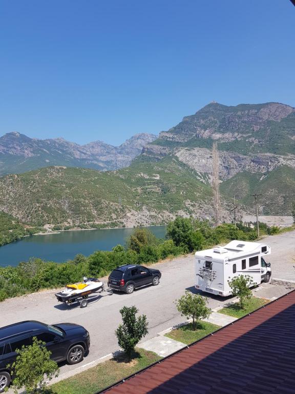 Una caravana y un camión estacionados en un estacionamiento junto a un lago en Lugina e Komanit en Koman