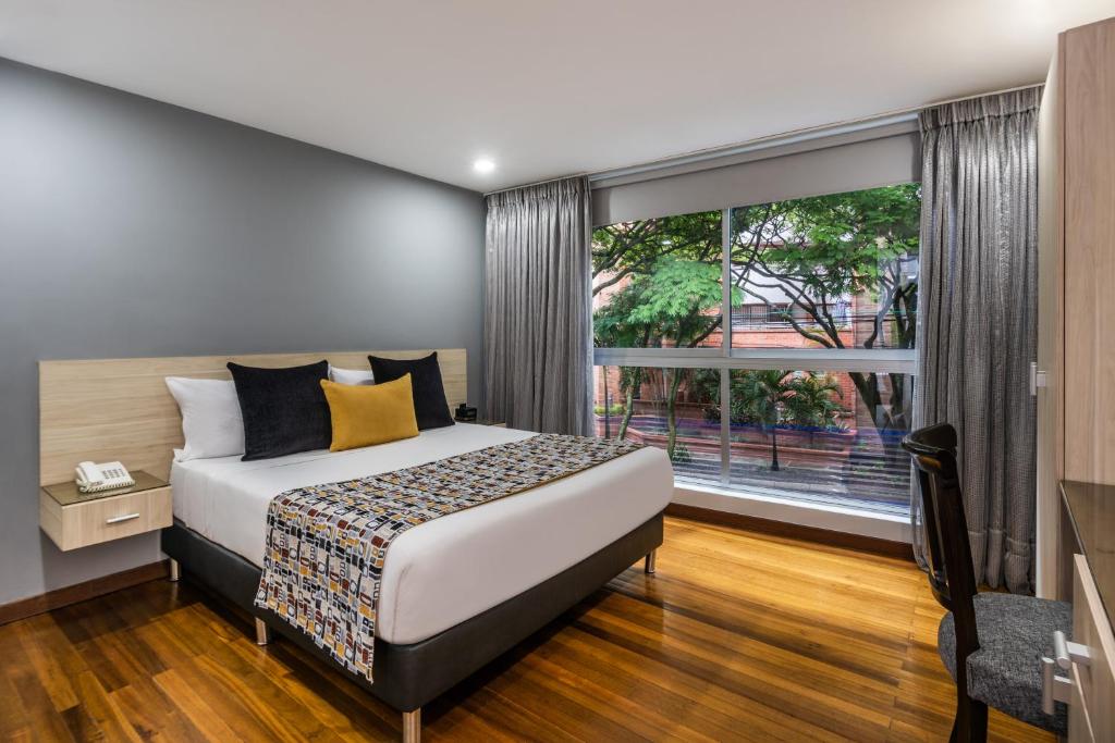 a bedroom with a bed and a large window at Hotel Asturias Medellin in Medellín
