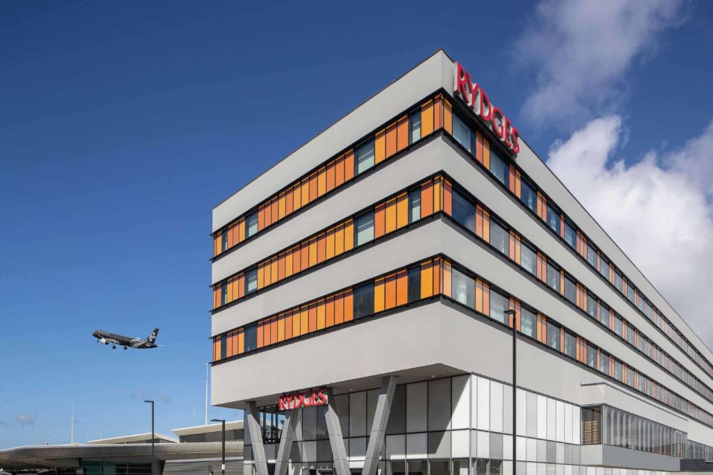 a hotel building with a plane in the sky at Rydges Wellington Airport in Wellington