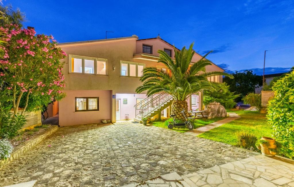 a house with a palm tree and a stone driveway at Viola Medulin in Medulin