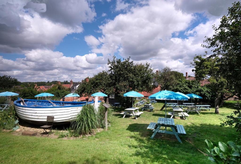 a boat sitting on the grass with tables and umbrellas at The Ship At Dunwich in Dunwich